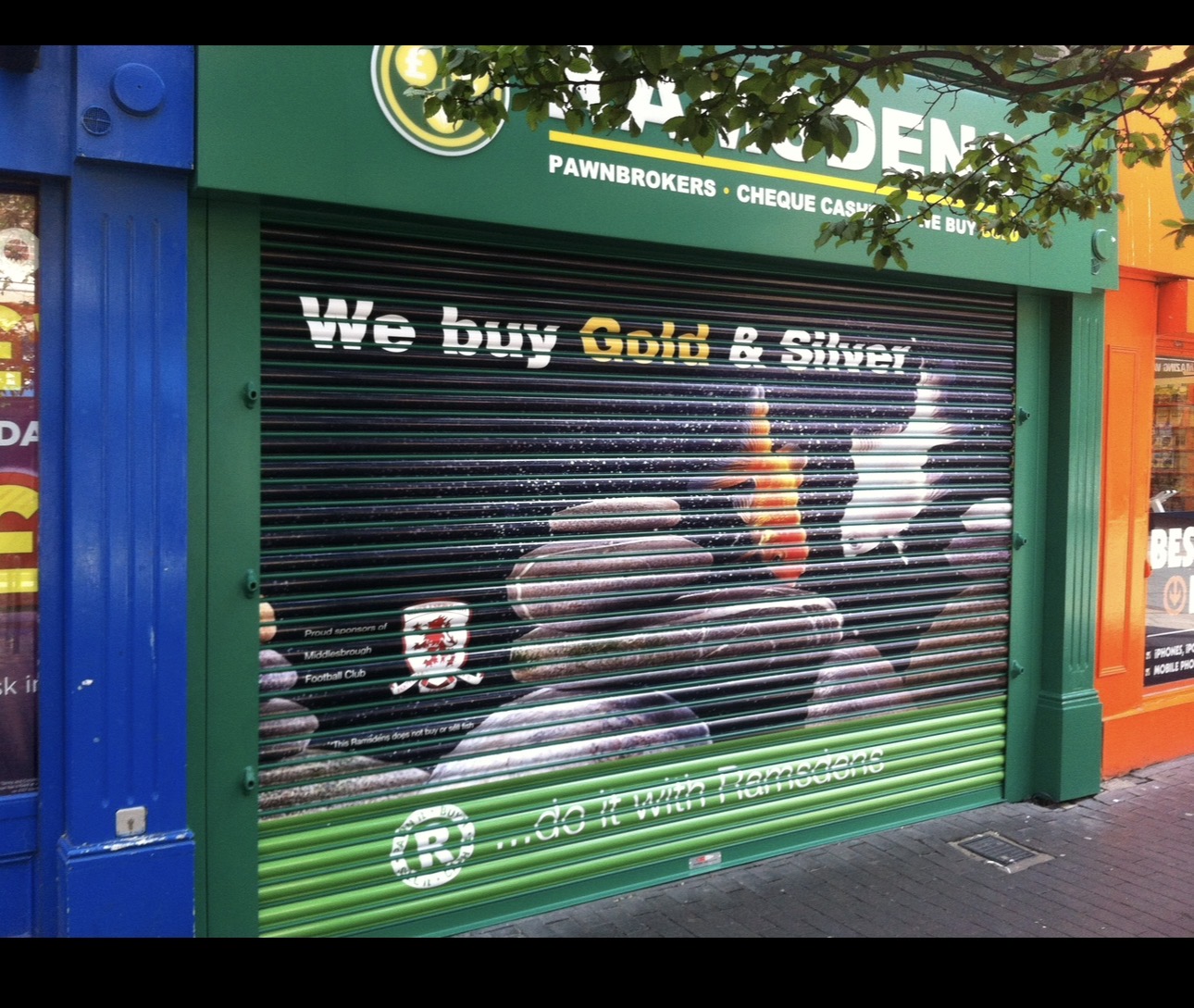 Ramsdens We Buy Gold and Silver advertising artwork across a closed roller shutter