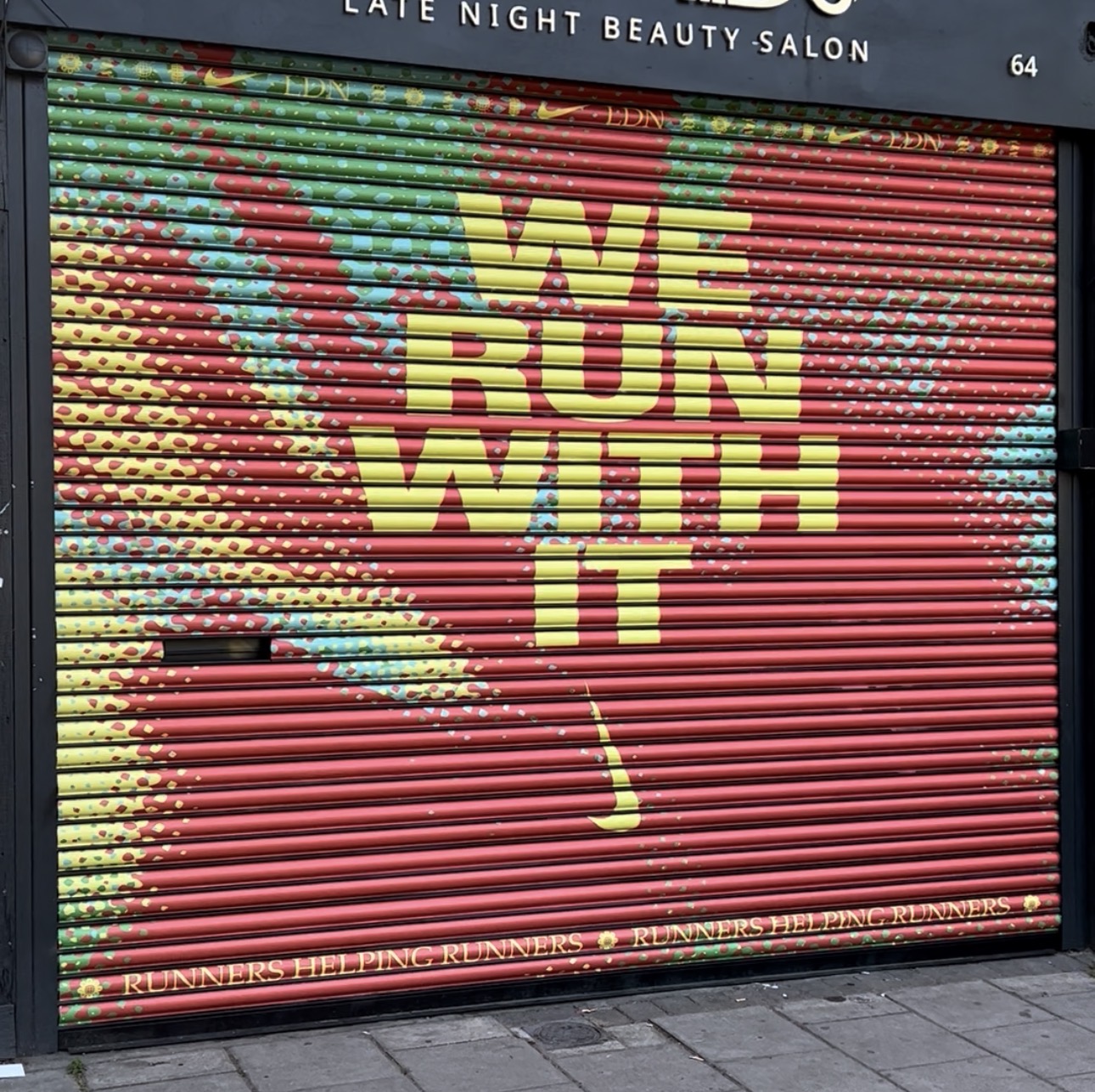 Nike We Run With It campaign artwork across a closed beauty salon roller shutter